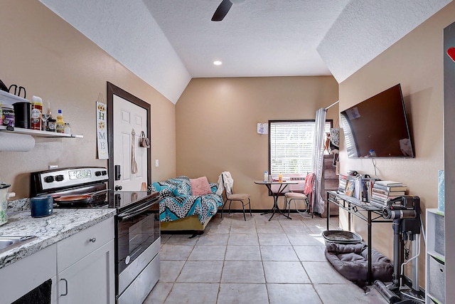 kitchen featuring stainless steel electric stove, vaulted ceiling, white cabinetry, light stone countertops, and light tile patterned floors