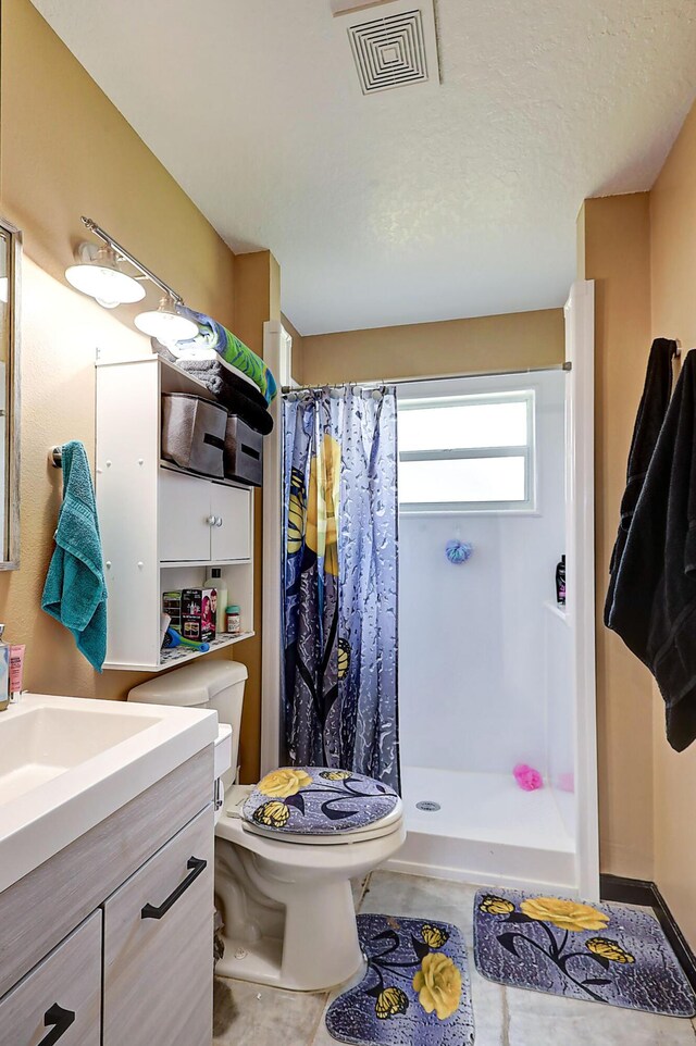 bathroom featuring a shower with shower curtain, vanity, tile patterned flooring, a textured ceiling, and toilet