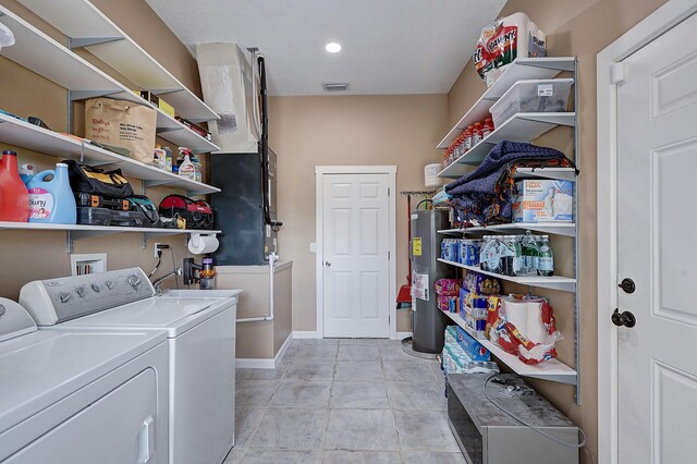 laundry area with water heater, light tile patterned floors, and washing machine and clothes dryer