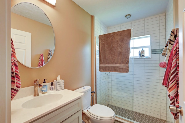 bathroom with a tile shower, vanity, and toilet