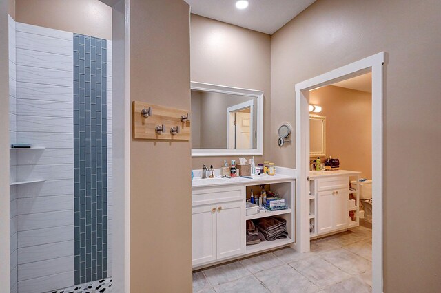 bathroom featuring tile patterned flooring, a tile shower, vanity, and toilet