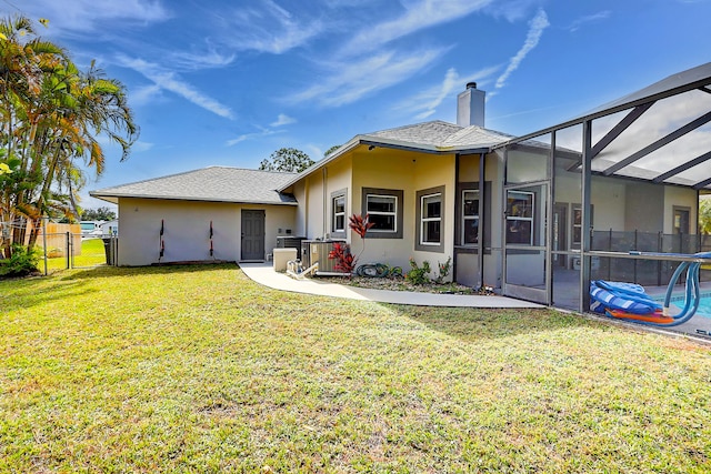 rear view of property with central AC unit, a lawn, and a lanai