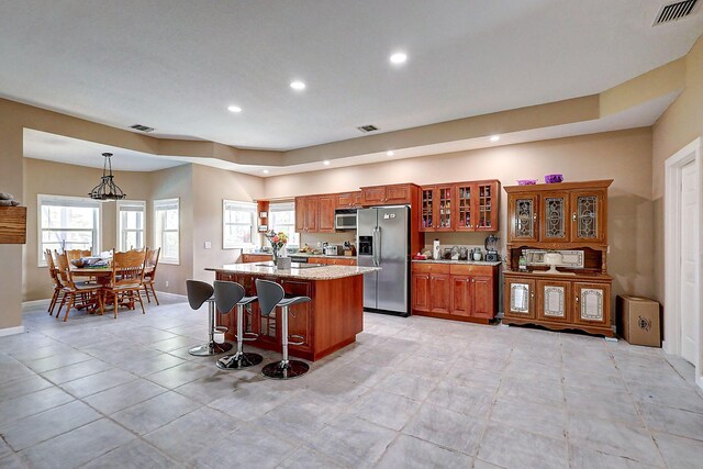 kitchen with light tile patterned flooring, a center island, stainless steel appliances, and pendant lighting