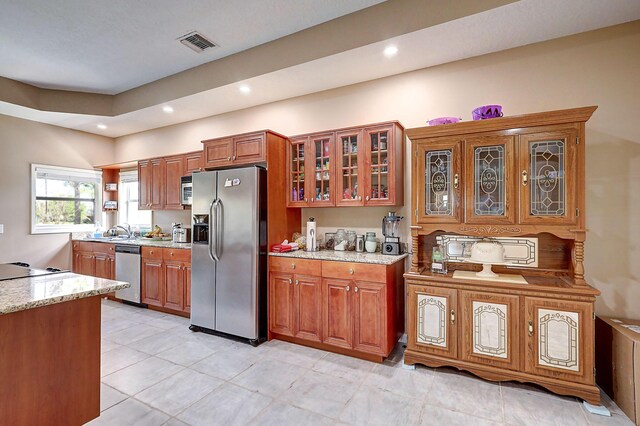 kitchen featuring sink, appliances with stainless steel finishes, light stone counters, and light tile patterned floors