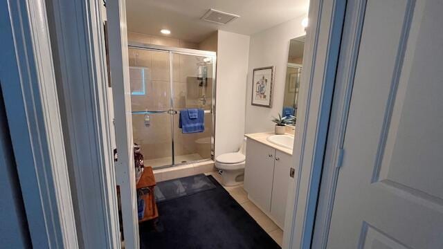 bathroom with walk in shower, tile patterned floors, vanity, and toilet