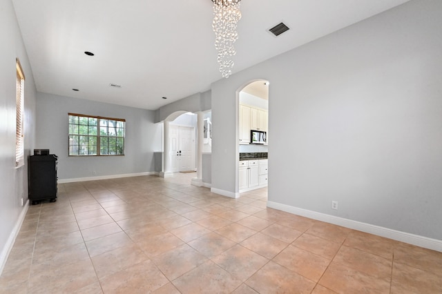 unfurnished living room featuring an inviting chandelier and light tile patterned floors