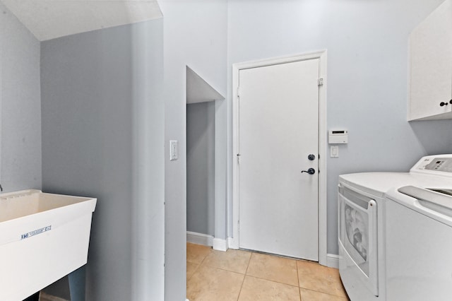 clothes washing area featuring cabinets, light tile patterned floors, sink, and washing machine and clothes dryer