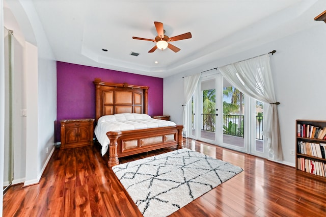 bedroom featuring ceiling fan, dark hardwood / wood-style floors, a tray ceiling, french doors, and access to outside