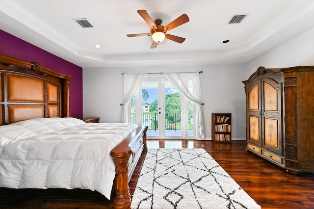 bedroom with french doors, dark hardwood / wood-style flooring, access to exterior, ceiling fan, and a raised ceiling