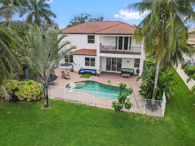 rear view of property with a fenced in pool, a patio, a balcony, and a yard