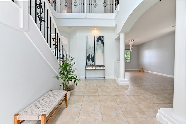 foyer with ornate columns, a towering ceiling, and light tile patterned flooring