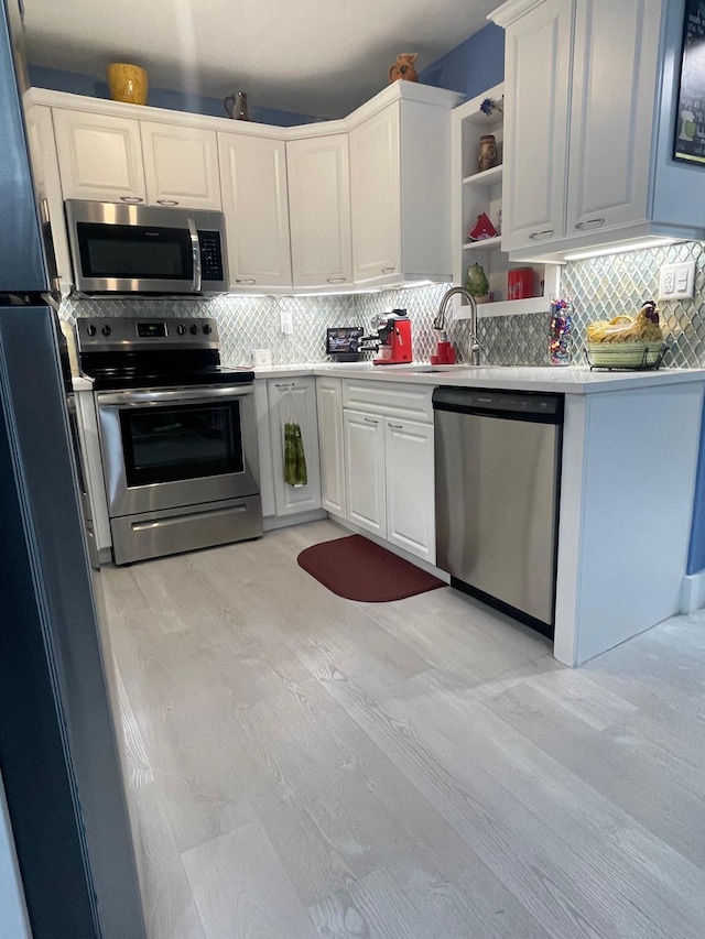 kitchen featuring sink, stainless steel appliances, tasteful backsplash, and white cabinets