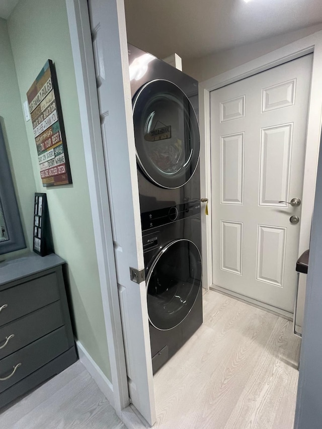 clothes washing area with stacked washer and dryer and light wood-type flooring