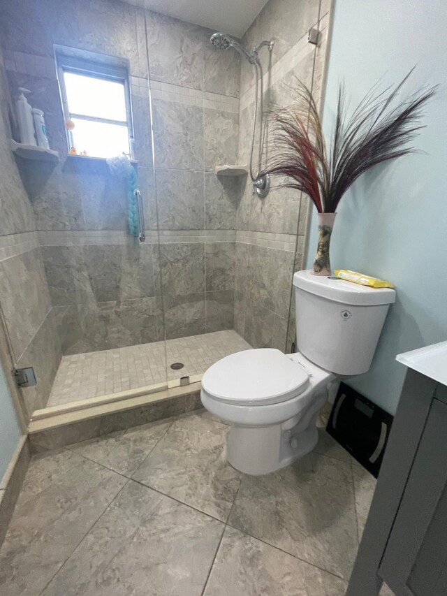 bathroom with a shower with shower door, toilet, vanity, and tile patterned floors