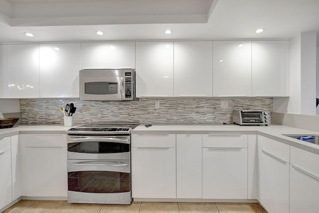 kitchen with appliances with stainless steel finishes, light tile patterned floors, and white cabinetry