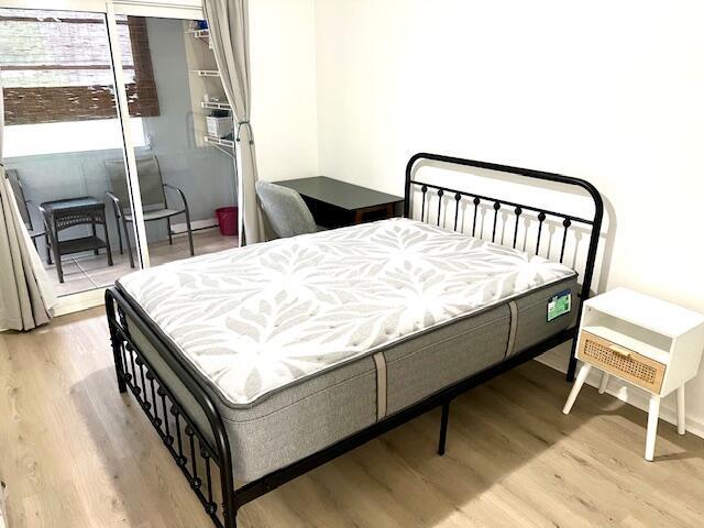 bedroom with light hardwood / wood-style floors and a baseboard radiator