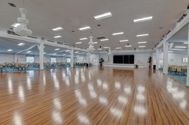 workout area with a chandelier and light hardwood / wood-style flooring