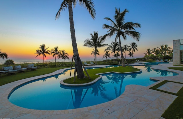 pool at dusk with a lawn and a patio