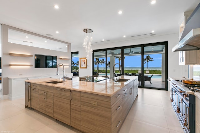 kitchen with hanging light fixtures, sink, range hood, and a large island