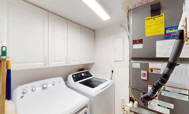 laundry area featuring washing machine and dryer, heating unit, and cabinets