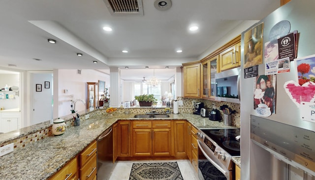 kitchen with sink, tasteful backsplash, light stone counters, and stainless steel appliances