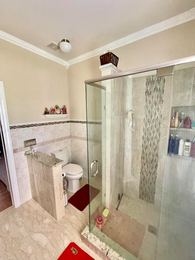 bathroom featuring tile patterned floors, an enclosed shower, tile walls, crown molding, and toilet