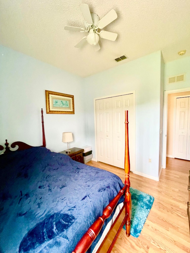 bedroom featuring a textured ceiling, light hardwood / wood-style flooring, ceiling fan, and a closet