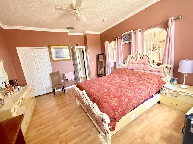 bedroom featuring ornamental molding, light wood-type flooring, a closet, a textured ceiling, and ceiling fan