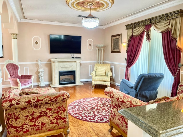 living room with hardwood / wood-style floors, ornamental molding, a tile fireplace, and a textured ceiling