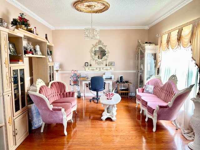 sitting room with hardwood / wood-style floors, crown molding, an inviting chandelier, and a textured ceiling