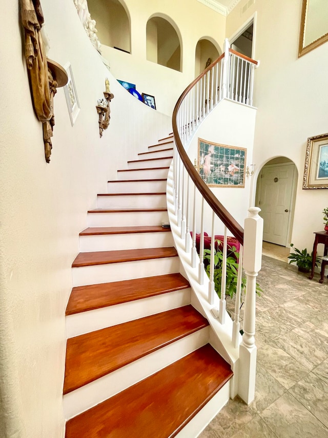 staircase featuring a high ceiling and light tile patterned flooring