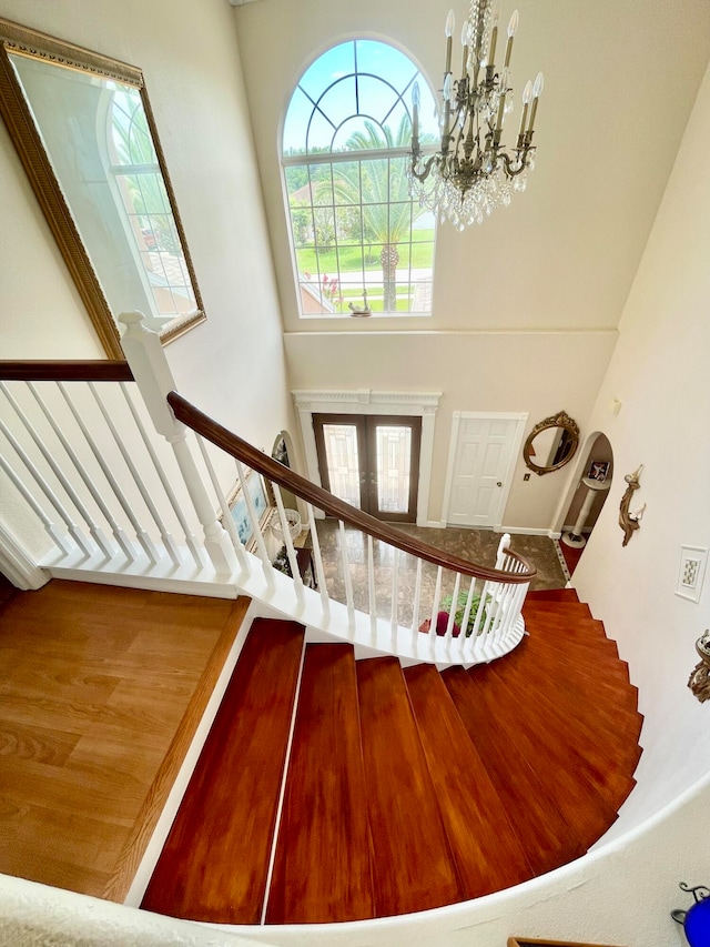 staircase featuring hardwood / wood-style flooring, a high ceiling, and a chandelier