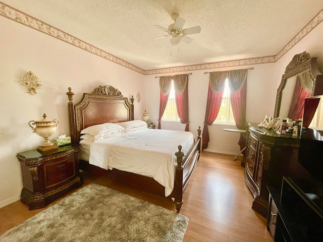 bedroom with ceiling fan, wood-type flooring, and a textured ceiling