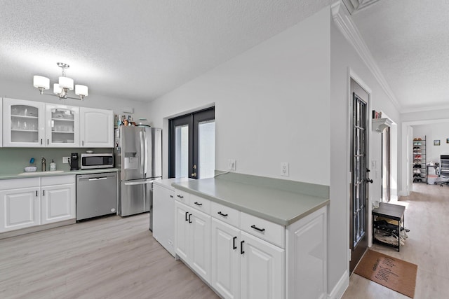 kitchen featuring a textured ceiling, light hardwood / wood-style flooring, french doors, crown molding, and stainless steel appliances