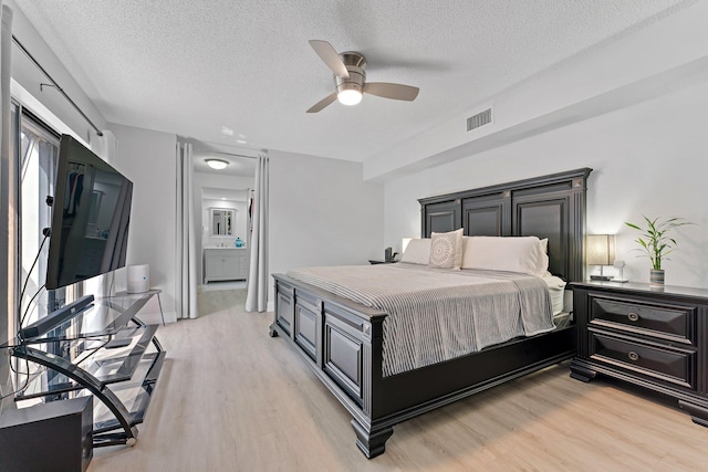 bedroom featuring ceiling fan, light hardwood / wood-style floors, and a textured ceiling