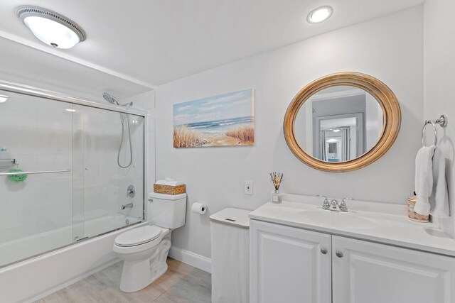 full bathroom with toilet, bath / shower combo with glass door, and vanity