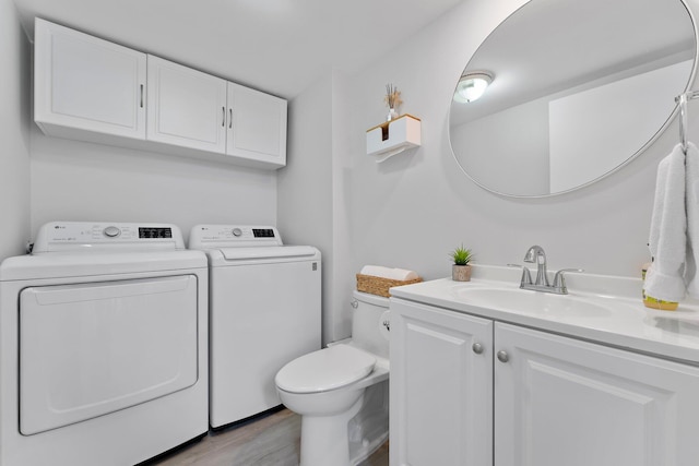 washroom featuring washing machine and dryer, sink, and light hardwood / wood-style floors