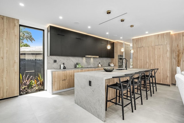 kitchen featuring a kitchen island with sink, pendant lighting, tasteful backsplash, and a breakfast bar area