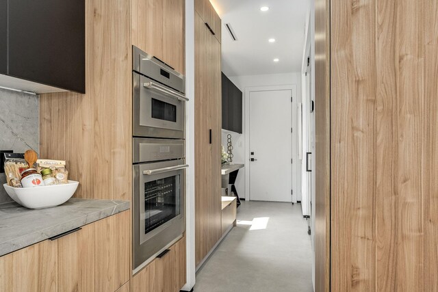 kitchen with a barn door, light brown cabinetry, and double oven