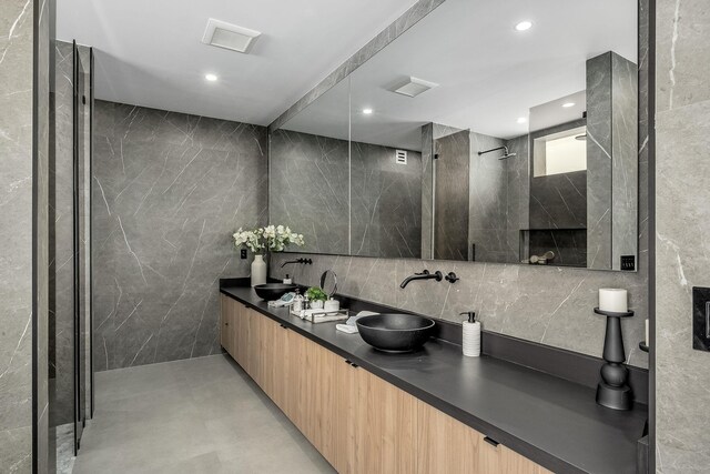 bathroom featuring tiled shower, tile walls, and vanity