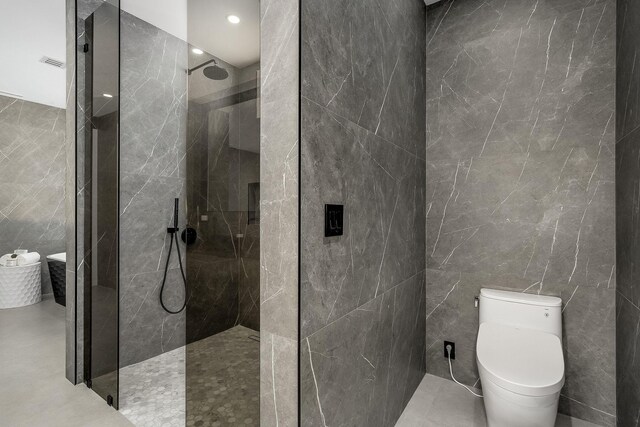 bathroom featuring tiled shower, tile walls, toilet, and tile patterned floors