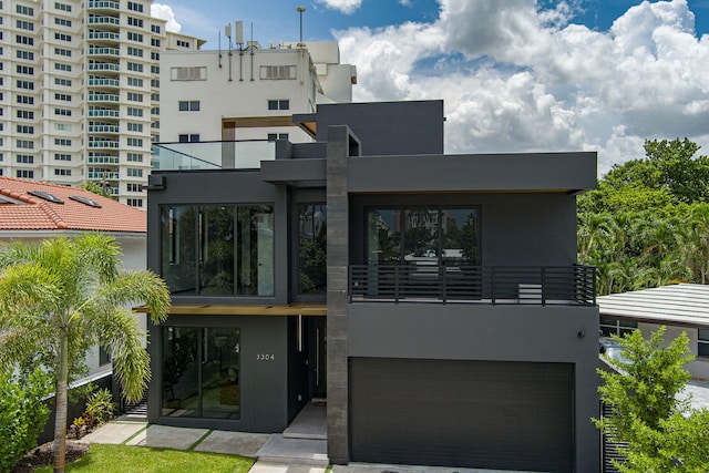 rear view of property featuring a balcony and a garage