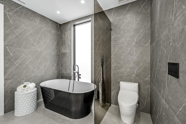 bathroom with tile walls, toilet, and a tub