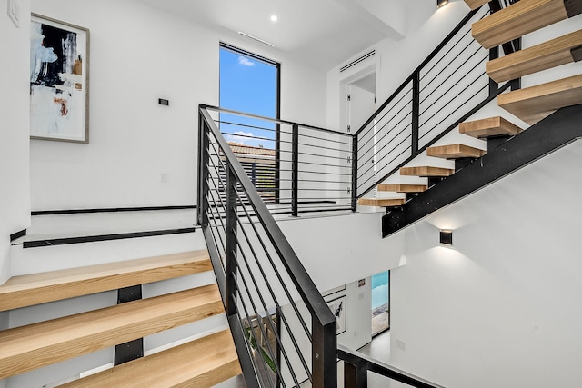 stairway featuring hardwood / wood-style flooring, a high ceiling, and a wealth of natural light