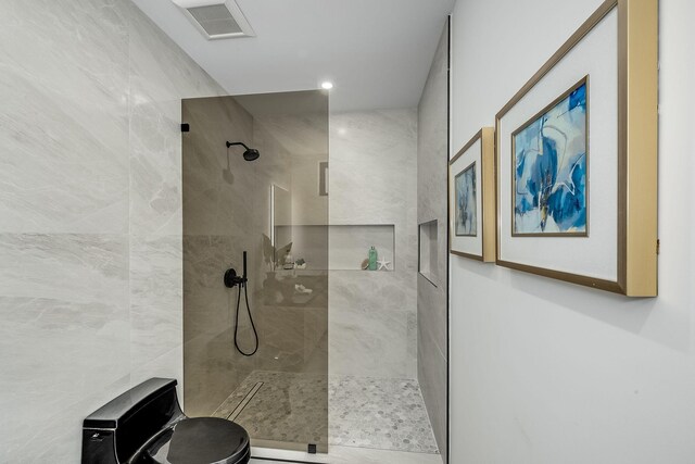 bathroom featuring toilet and a tile shower