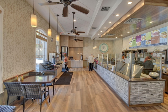 living room featuring light hardwood / wood-style flooring, ceiling fan, and a towering ceiling