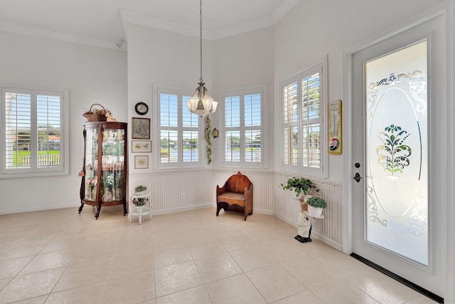 foyer with crown molding, light tile patterned flooring, and a chandelier