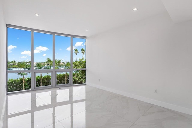 unfurnished room with floor to ceiling windows and light tile patterned floors