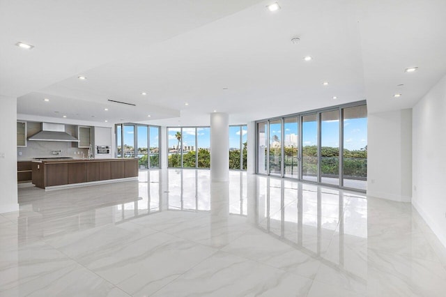 unfurnished living room featuring expansive windows, marble finish floor, baseboards, and recessed lighting