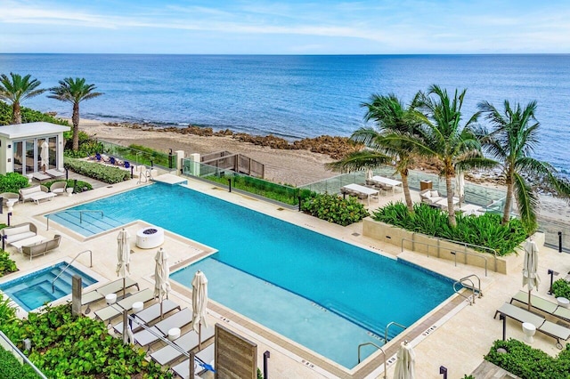 community pool with a water view, fence, and a patio